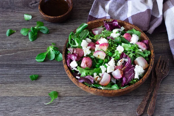 Mixed salad with baby leaves of red lettuce, arugula, corn salad, radish, green peas and ricotta cheese with olive oil and balsamic vinegar dressing. Healthy food.