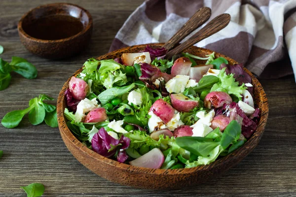 Mixed salad with baby leaves of red lettuce, arugula, corn salad, radish, green peas and ricotta cheese with olive oil and balsamic vinegar dressing. Healthy food.