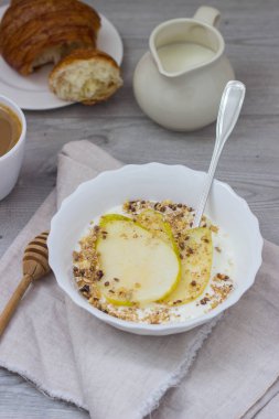 Sağlıklı kahvaltı kase: armut, bal ve granola ahşap zemin üzerine yoğurtlu