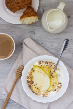 Sağlıklı kahvaltı kase: armut, bal ve granola ahşap zemin üzerine yoğurtlu
