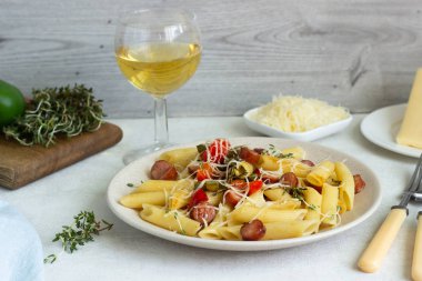 Sosis, dolmalık biber, peynir ve kekik Beyaz ahşap zemin üzerinde plaka ile penne makarna. 