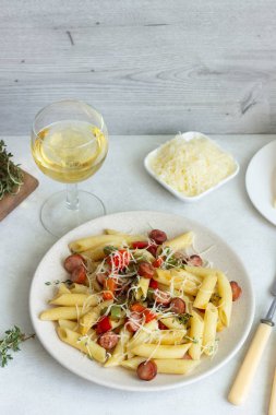 Sosis, dolmalık biber, peynir ve kekik Beyaz ahşap zemin üzerinde plaka ile penne makarna. 