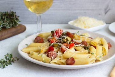 Sosis, dolmalık biber, peynir ve kekik Beyaz ahşap zemin üzerinde plaka ile penne makarna. 