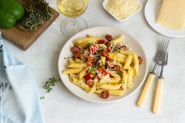 Sosis, dolmalık biber, peynir ve kekik Beyaz ahşap zemin üzerinde plaka ile penne makarna. 