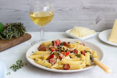 Sosis, dolmalık biber, peynir ve kekik Beyaz ahşap zemin üzerinde plaka ile penne makarna. 