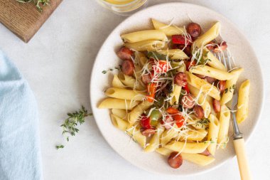 Sosis, dolmalık biber, peynir ve kekik Beyaz ahşap zemin üzerinde plaka ile penne makarna. 