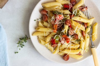 Sosis, dolmalık biber, peynir ve kekik Beyaz ahşap zemin üzerinde plaka ile penne makarna. 