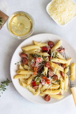 Sosis, dolmalık biber, peynir ve kekik Beyaz ahşap zemin üzerinde plaka ile penne makarna. 