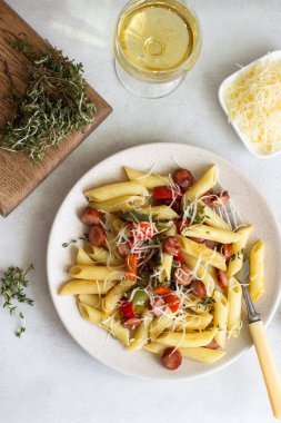 Sosis, dolmalık biber, peynir ve kekik Beyaz ahşap zemin üzerinde plaka ile penne makarna. 