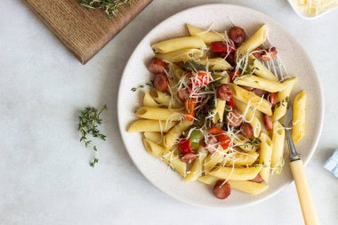 Sosis, dolmalık biber, peynir ve kekik Beyaz ahşap zemin üzerinde plaka ile penne makarna. 