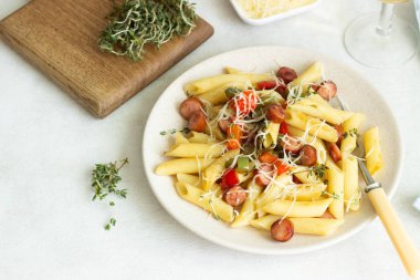 Sosis, dolmalık biber, peynir ve kekik Beyaz ahşap zemin üzerinde plaka ile penne makarna. 