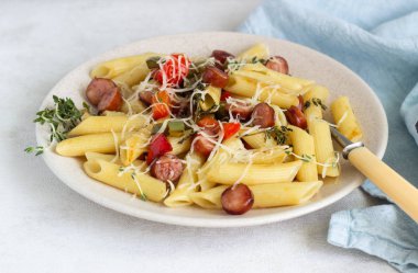 Sosis, dolmalık biber, peynir ve kekik Beyaz ahşap zemin üzerinde plaka ile penne makarna. 