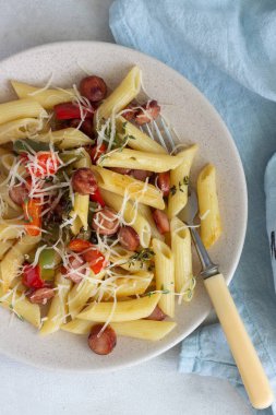 Sosis, dolmalık biber, peynir ve kekik Beyaz ahşap zemin üzerinde plaka ile penne makarna. 