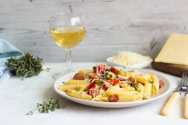 Sosis, dolmalık biber, peynir ve kekik Beyaz ahşap zemin üzerinde plaka ile penne makarna. 