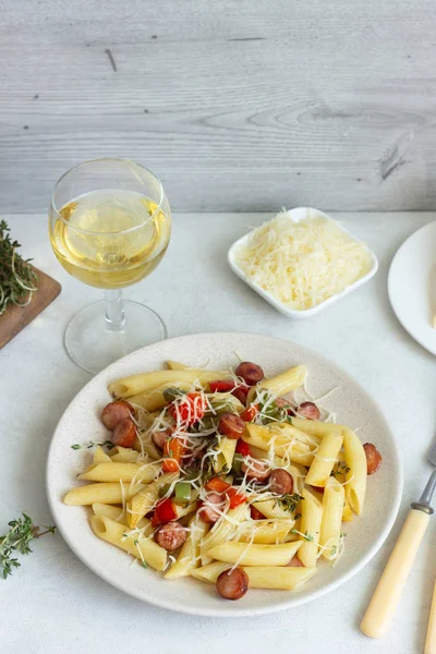 Sosis, dolmalık biber, peynir ve kekik Beyaz ahşap zemin üzerinde plaka ile penne makarna. 