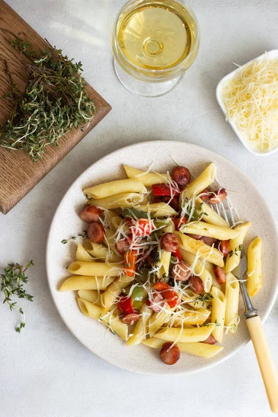 Sosis, dolmalık biber, peynir ve kekik Beyaz ahşap zemin üzerinde plaka ile penne makarna. 