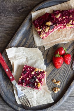 Kek veya çilek, çikolata ve cevizli tatlı ekmek kırıntısı (streusel) bir parşömen kağıt üzerinde seçici odak ile tatlılar yığını. Çilek barlar. Kare şekli. Geleneksel tatlar karışımı