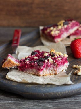 Kek veya çilek, çikolata ve cevizli tatlı ekmek kırıntısı (streusel) bir parşömen kağıt üzerinde seçici odak ile tatlılar yığını. Çilek barlar. Kare şekli. Geleneksel tatlar karışımı