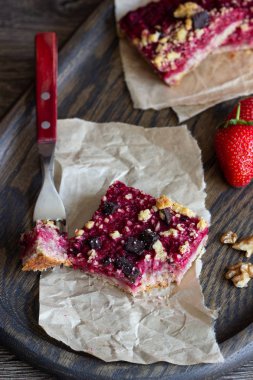 Kek veya çilek, çikolata ve cevizli tatlı ekmek kırıntısı (streusel) bir parşömen kağıt üzerinde seçici odak ile tatlılar yığını. Çilek barlar. Kare şekli. Geleneksel tatlar karışımı