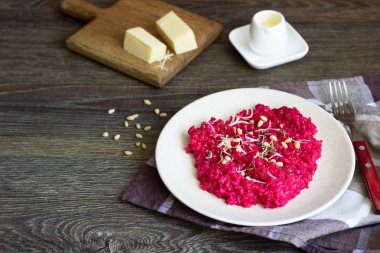 Parmesan peyniri, çam fıstığı ve kekik bir plaka üzerinde eski ahşap arka plan üzerinde kırmızı pancar risotto.