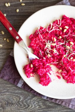 Parmesan peyniri, çam fıstığı ve kekik bir plaka üzerinde eski ahşap arka plan üzerinde kırmızı pancar risotto.