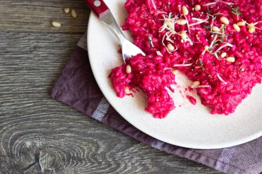 Parmesan peyniri, çam fıstığı ve kekik bir plaka üzerinde eski ahşap arka plan üzerinde kırmızı pancar risotto.