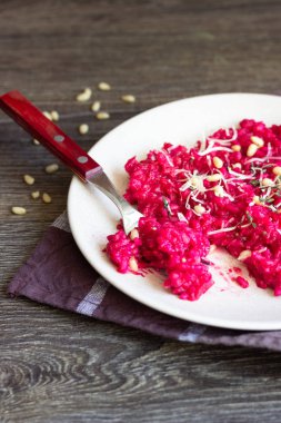 Parmesan peyniri, çam fıstığı ve kekik bir plaka üzerinde eski ahşap arka plan üzerinde kırmızı pancar risotto.