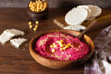 Kavrulmuş Pancar humus kase nohut, susam ve sağlıklı yongaları üzerinde ahşap yüzey. Aperatifler kavramı