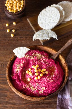 Kavrulmuş Pancar humus kase nohut, susam ve sağlıklı yongaları üzerinde ahşap yüzey. Aperatifler kavramı