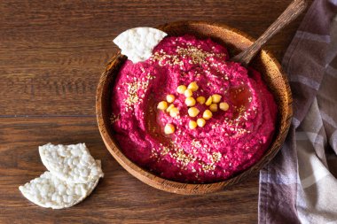 Kavrulmuş Pancar humus kase nohut, susam ve sağlıklı yongaları üzerinde ahşap yüzey. Aperatifler kavramı