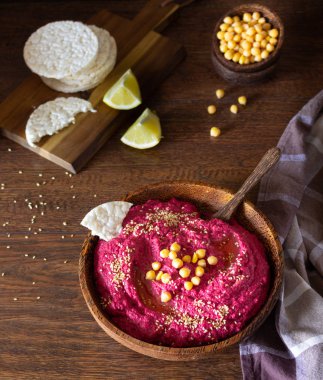 Kavrulmuş Pancar humus kase nohut, susam ve sağlıklı yongaları üzerinde ahşap yüzey. Aperatifler kavramı