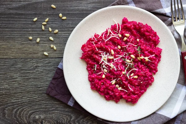 Parmesan peyniri, çam fıstığı ve kekik bir plaka üzerinde eski ahşap arka plan üzerinde kırmızı pancar risotto.