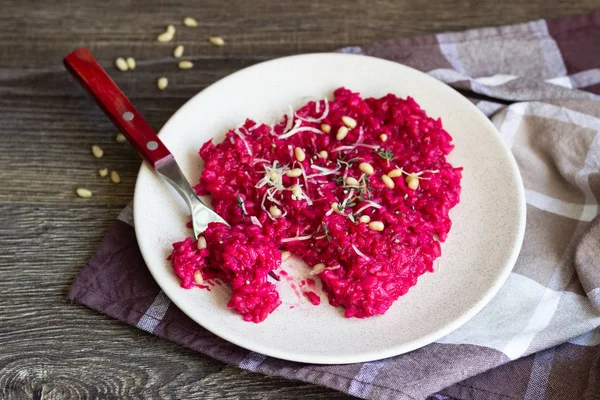 Parmesan peyniri, çam fıstığı ve kekik bir plaka üzerinde eski ahşap arka plan üzerinde kırmızı pancar risotto.