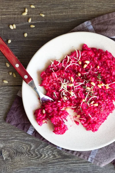 Parmesan peyniri, çam fıstığı ve kekik bir plaka üzerinde eski ahşap arka plan üzerinde kırmızı pancar risotto.