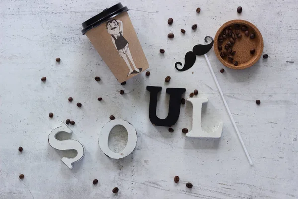 Flat lay with a cup of coffee, coffee beans, letters and a stick with mustache. Lifestyle and blogger concept.