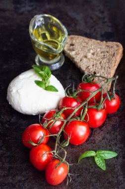 Taze fesleğen, mozzarella peyniri, zeytin yağı ve koyu arka plan üzerinde kiraz domates. İtalyan gıda veya maddeler arka plan. Caprese. Kopya alanı, üstten görünüm.