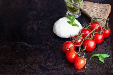 Taze fesleğen, mozzarella peyniri, zeytin yağı ve koyu arka plan üzerinde kiraz domates. İtalyan gıda veya maddeler arka plan. Caprese. Kopya alanı, üstten görünüm.