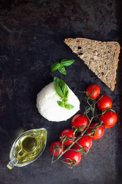 Taze fesleğen, mozzarella peyniri, zeytin yağı ve koyu arka plan üzerinde kiraz domates. İtalyan gıda veya maddeler arka plan. Caprese. Kopya alanı, üstten görünüm.