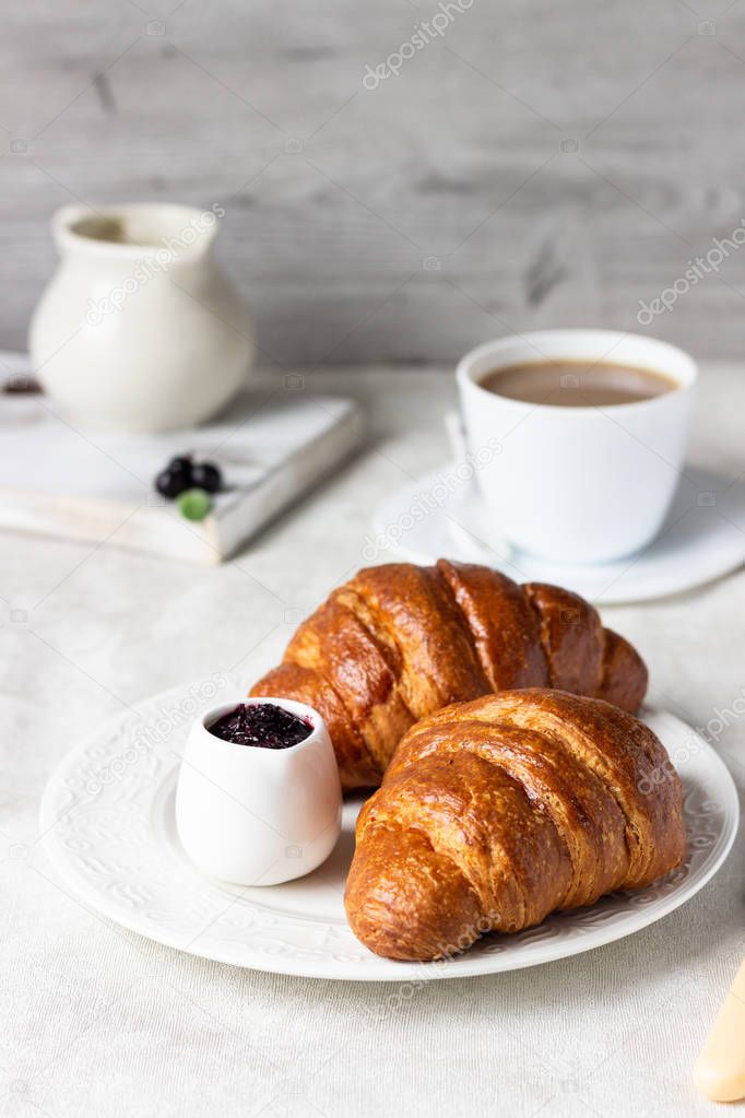 Delicious breakfast with fresh croissants and berries with cup of coffee on a light grey background