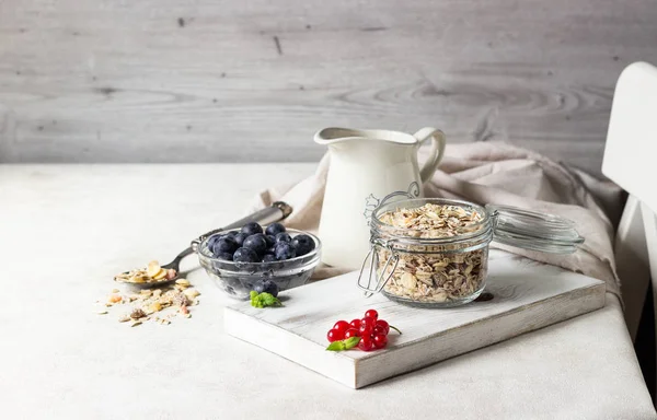 Ev yapımı granola açık cam kavanoz, süt, yaban mersini, frenk üzümü ve nane açık renkli, sağlıklı kahvaltı malzemeler üzerinde. Kopya alanı
