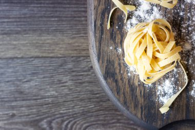 Ahşap kesme tahtası üzerinde ham tagliatelle makarna. El yapımı geleneksel makarna çeşitleri.