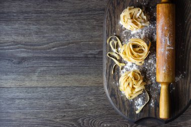 Ahşap kesme tahtası üzerinde ham tagliatelle makarna. El yapımı geleneksel makarna çeşitleri.