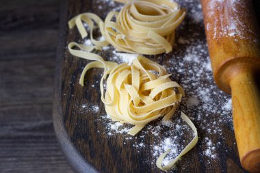 Ahşap kesme tahtası üzerinde ham tagliatelle makarna. El yapımı geleneksel makarna çeşitleri.