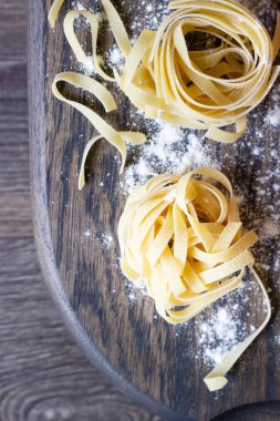 Ahşap kesme tahtası üzerinde ham tagliatelle makarna. El yapımı geleneksel makarna çeşitleri.
