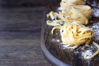 Ahşap kesme tahtası üzerinde ham tagliatelle makarna. El yapımı geleneksel makarna çeşitleri.