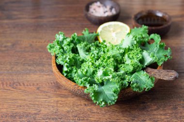 Taze yeşil kale ahşap kase limonlu ahşap arka plan üzerinde bırakır. Superfood. Seçici odak