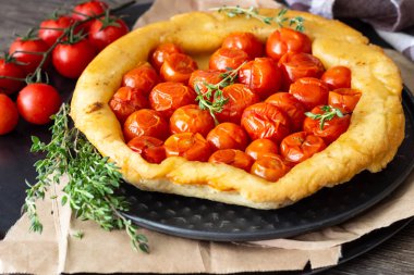 Puf böreği çiğ domatesli ve koyu ahşap zemin üzerine kekik kiraz domates ile ev yapımı tart. Domates tart tatin. Rustik tarzı.