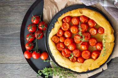 Puf böreği çiğ domatesli ve koyu ahşap zemin üzerine kekik kiraz domates ile ev yapımı tart. Domates tart tatin. Rustik tarzı.