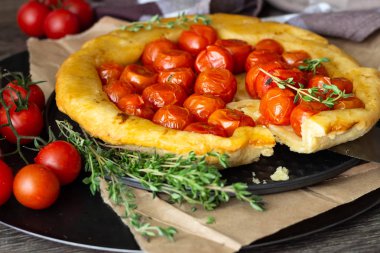 Puf böreği çiğ domatesli ve koyu ahşap zemin üzerine kekik kiraz domates ile ev yapımı tart. Domates tart tatin. Rustik tarzı.