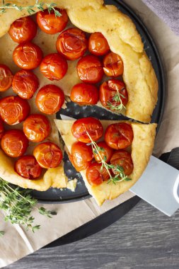 Puf böreği çiğ domatesli ve koyu ahşap zemin üzerine kekik kiraz domates ile ev yapımı tart. Domates tart tatin. Rustik tarzı.